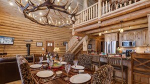 A wooden interior with a dining area, kitchen, and staircase. - Lumberjack Lodge (Island Park)