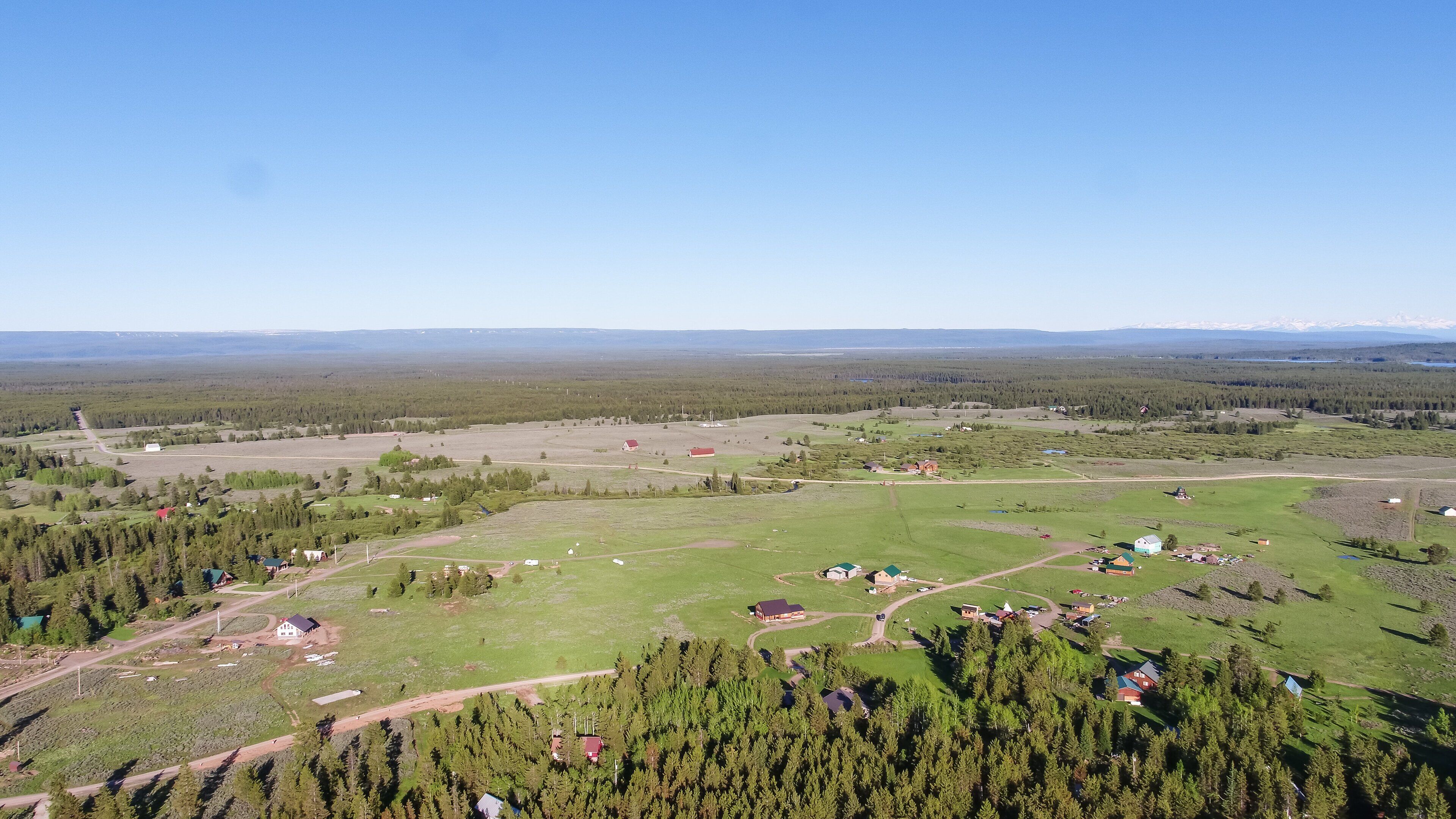 Une vue aérienne d’un paysage rural, avec des maisons dispersées, des routes et une vaste zone forestière.
