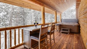 A wooden deck with a hot tub, bar area, and seating. - Lumberjack Lodge (Island Park)