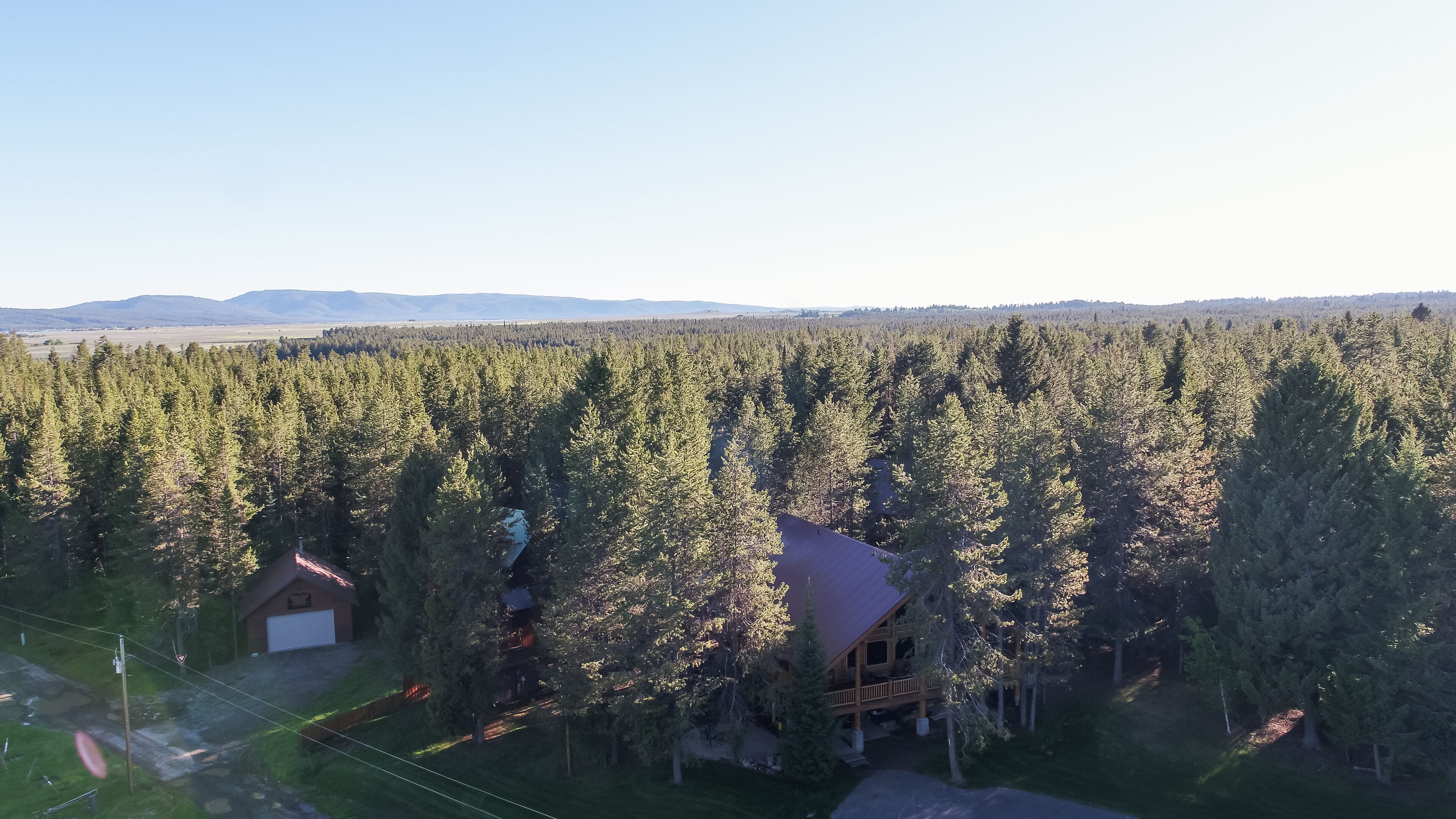 A lodge surrounded by dense forest with a clear view of distant mountains.