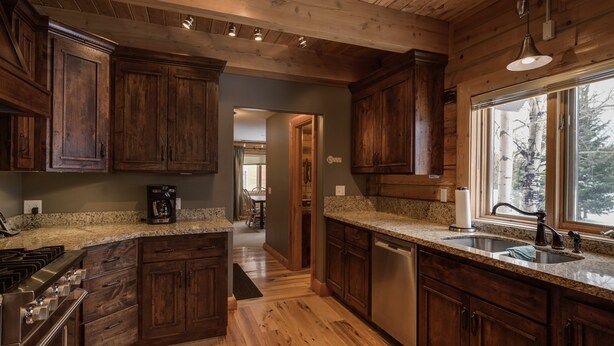 A kitchen with wooden cabinets, granite countertops, stainless steel appliances, and a large window providing a view of the outdoors. - Eagles Perch (Island Park)