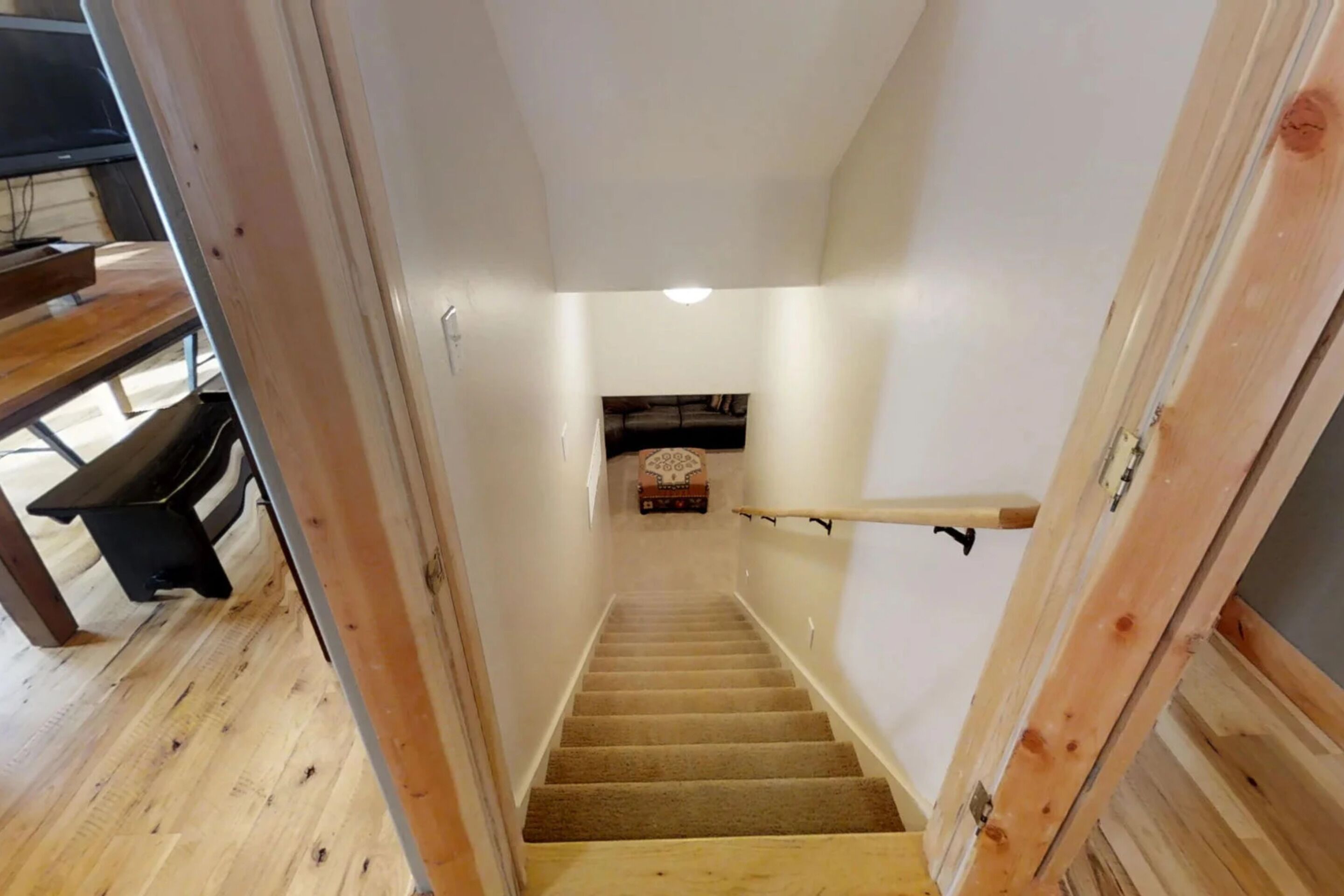 A wooden staircase with a handrail, carpeted steps, and a small shelf at the top.