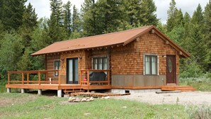 A wooden cabin with a deck, a covered porch, and a small front porch. - True Grit Adventure (Island Park)