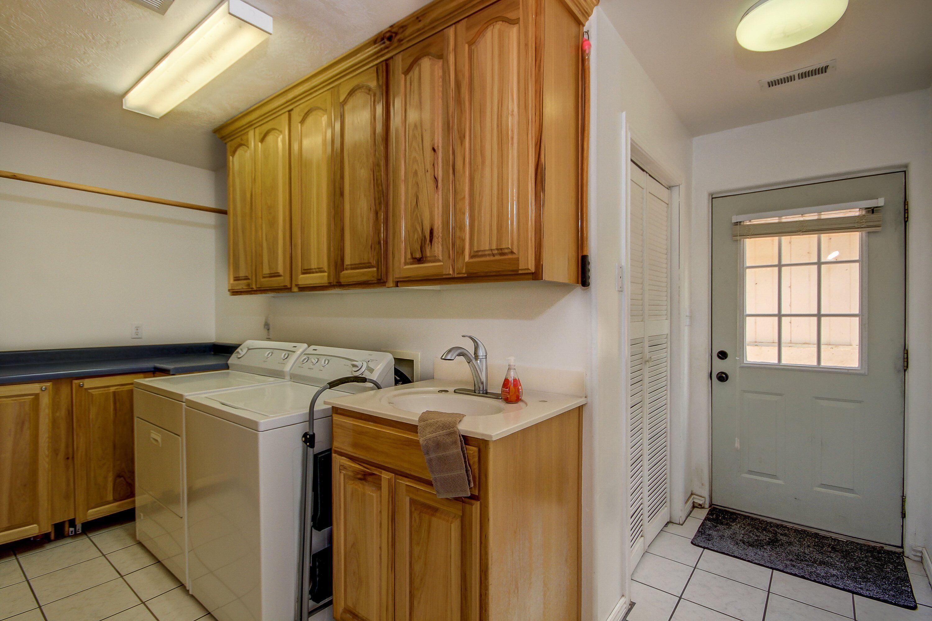 A laundry area with a washing machine, dryer, and wooden cabinets.