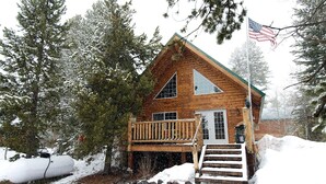 A wooden cabin with a balcony, surrounded by snow-covered trees.