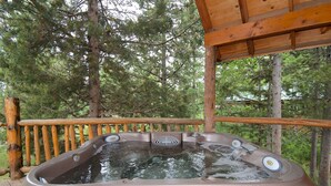A hot tub on a wooden deck surrounded by trees.