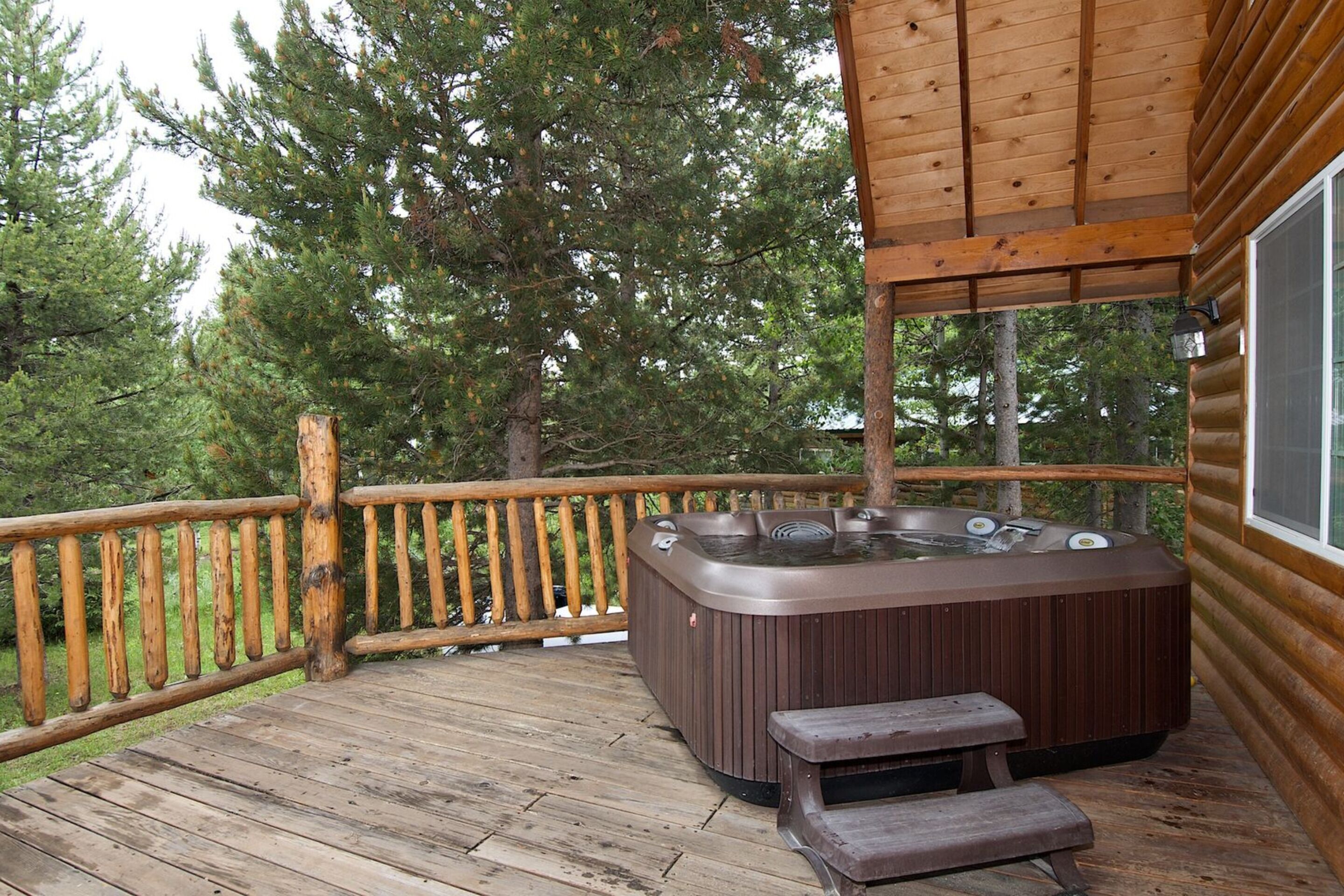 A wooden deck with a hot tub and a bench.