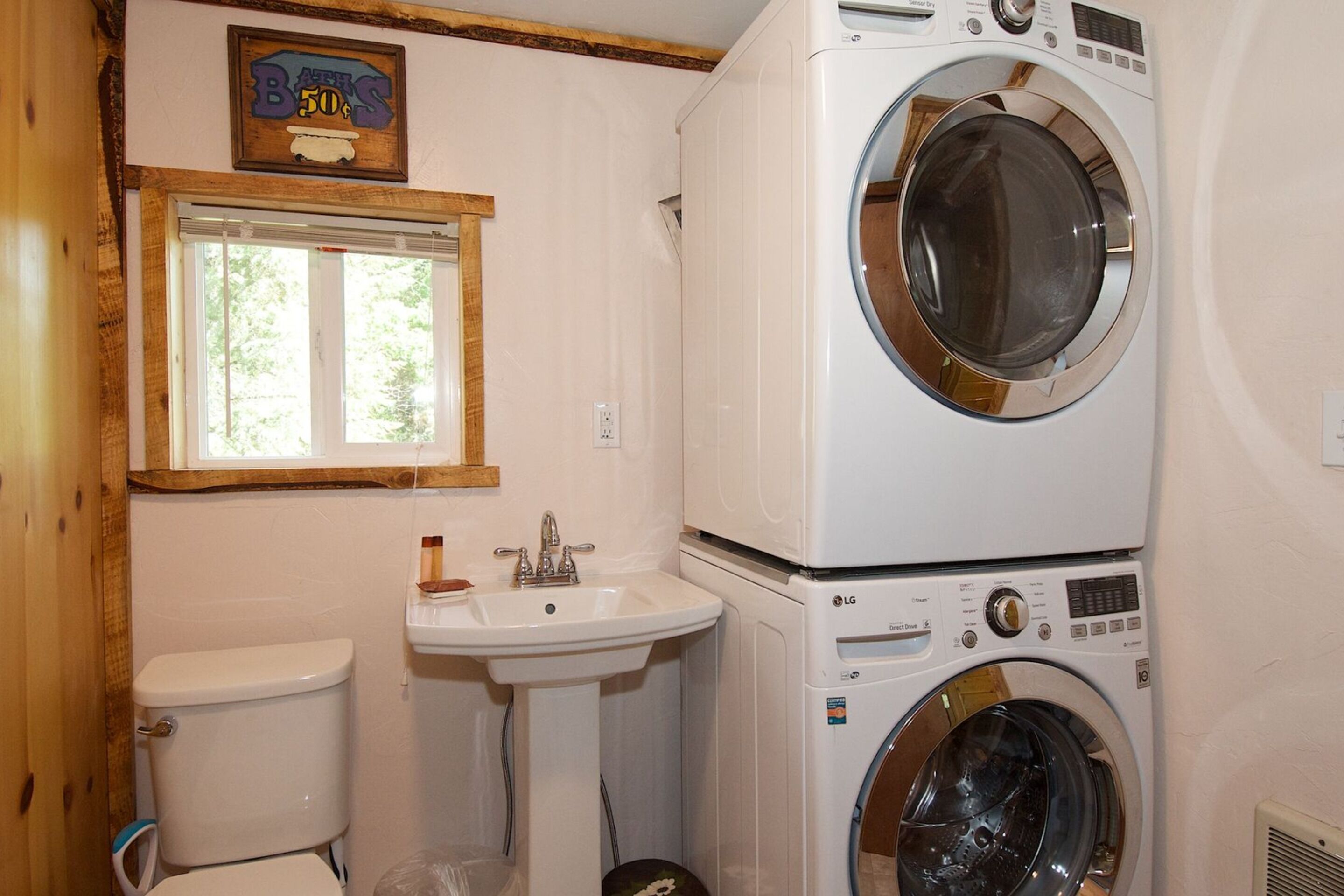 Ein kleines Badezimmer mit Toilette, Waschbecken und gestapeltem Waschtrockner.