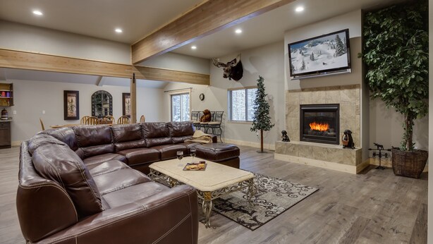 A spacious living room with a large leather sectional sofa, a fireplace, and a mounted deer head. - Buck Buck Moose (Island Park)
