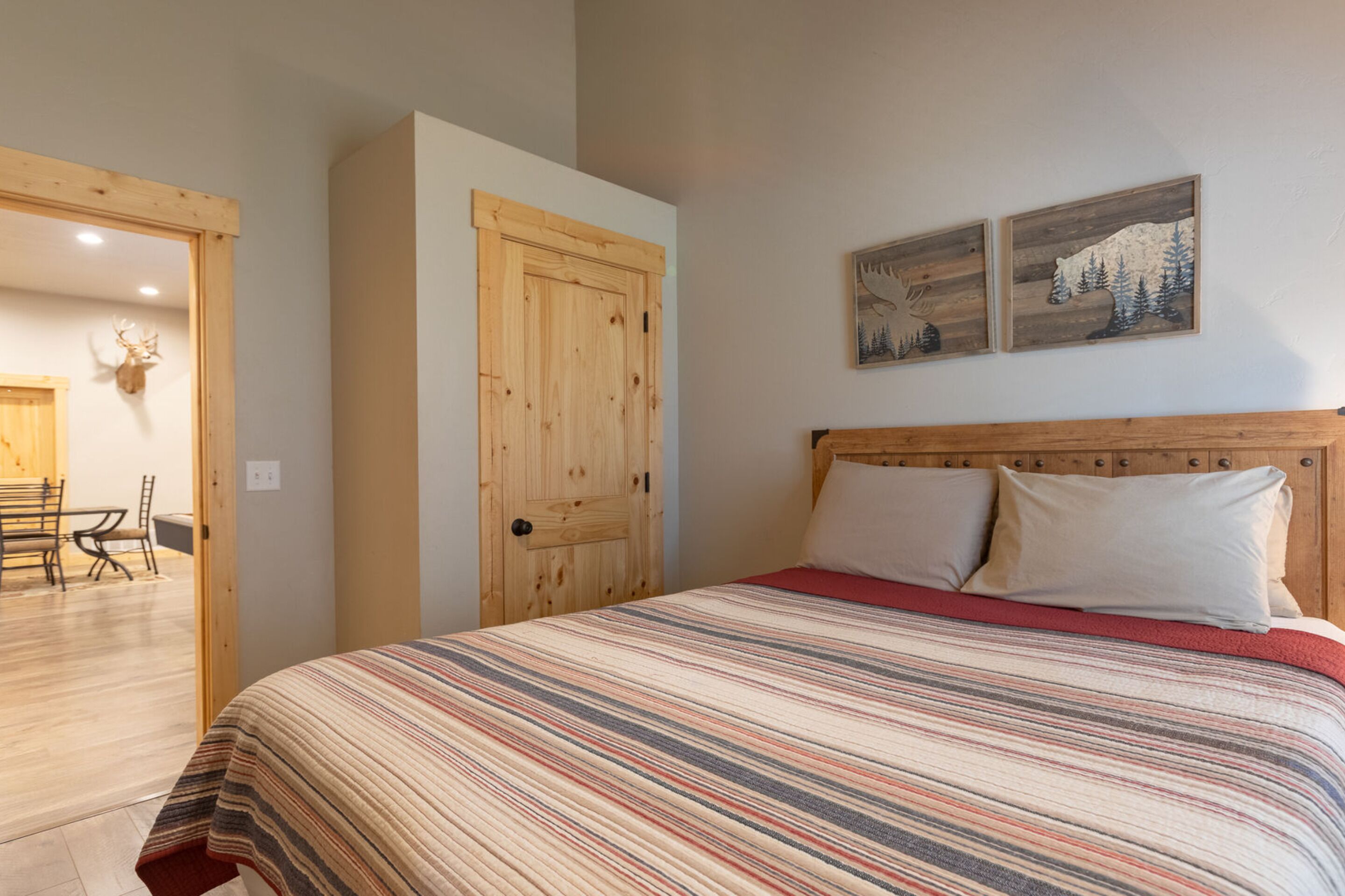 Une chambre à coucher avec une tête de lit en bois, une couvre-lit à rayures et deux tableaux accrochés au mur.