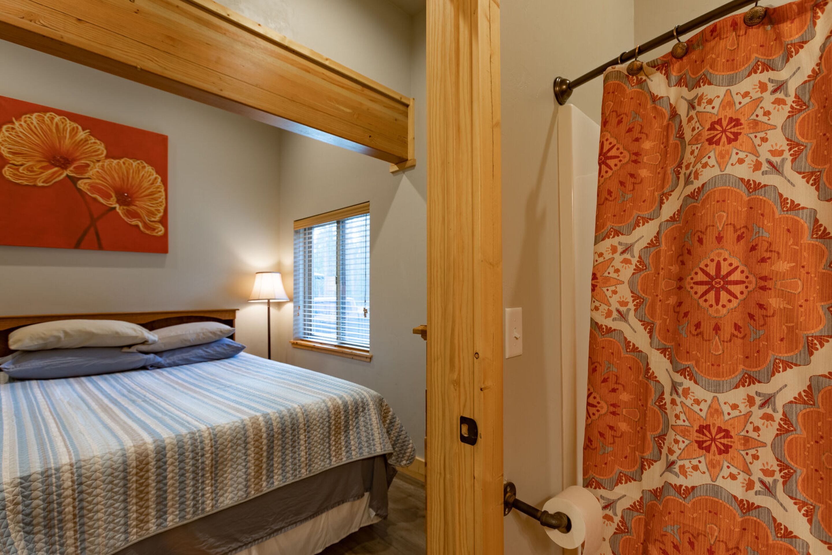 Een slaapkamer met een bed, een raam, een schilderij en een douchegordijn.