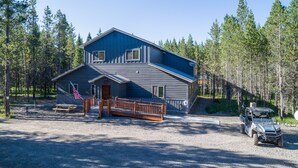 A two-story cabin with a deck, surrounded by a forest. - Buck Buck Moose (Island Park)