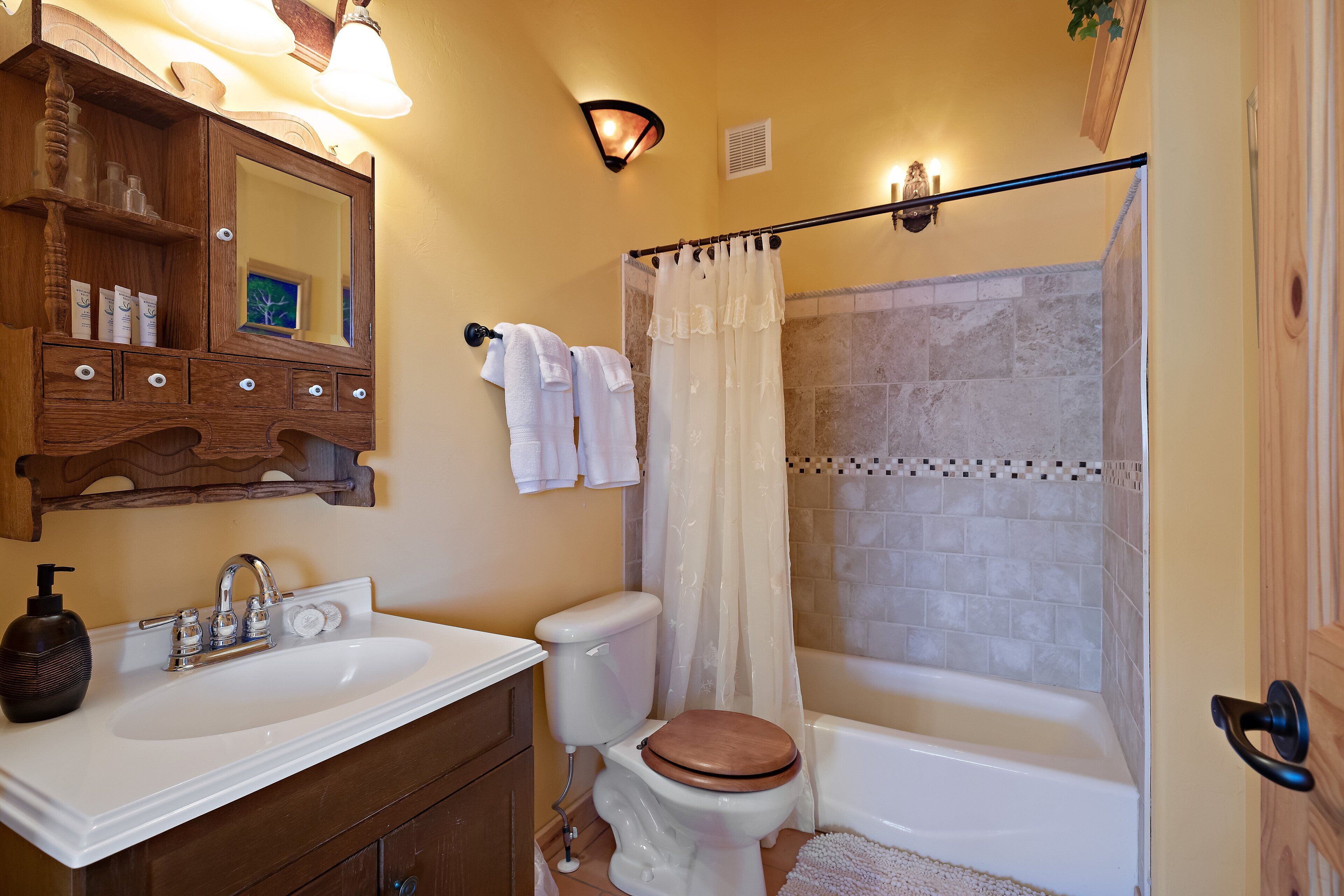 Une salle de bain avec un meuble-lavabo en bois, un évier, des toilettes et une baignoire.