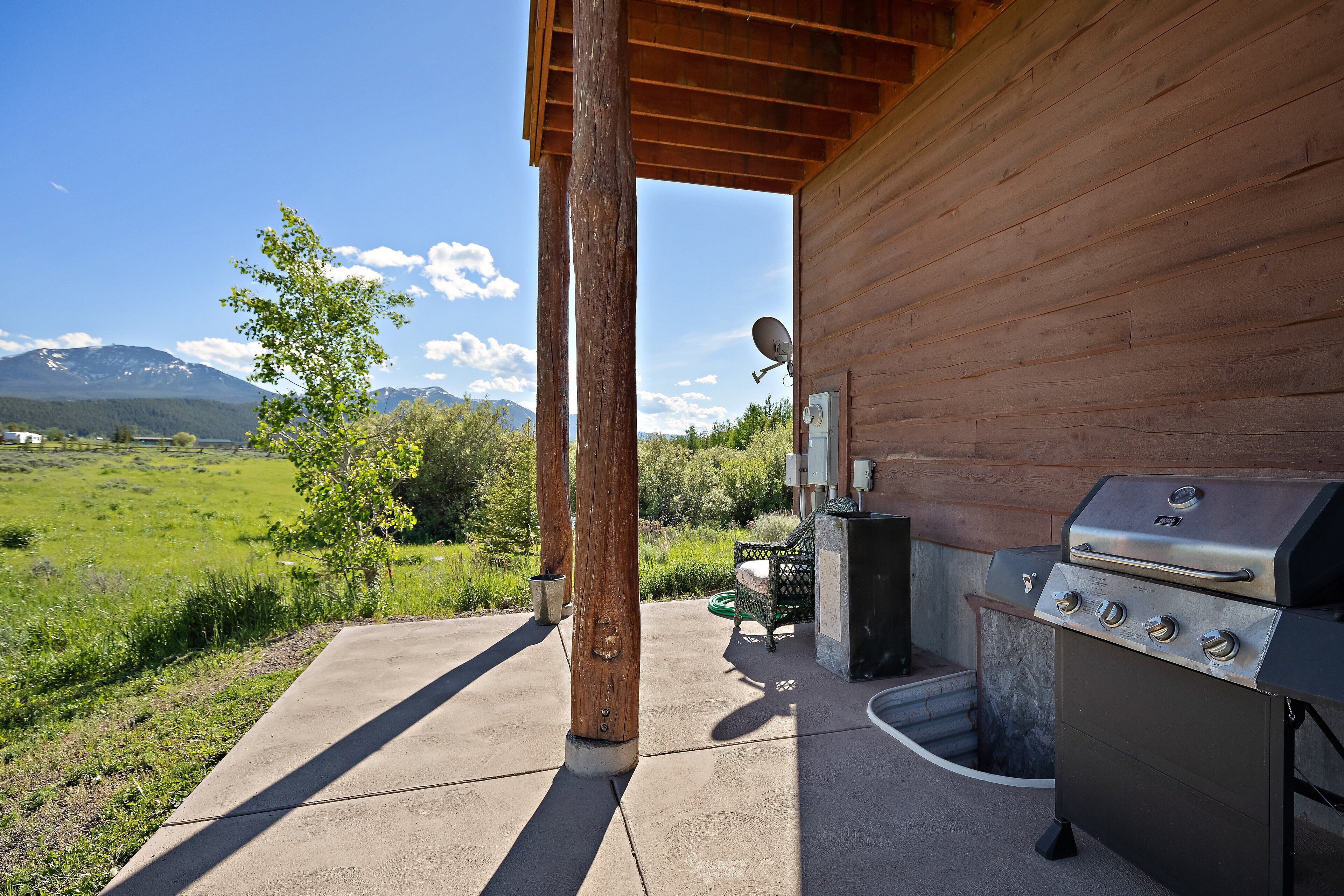 An outdoor patio with a barbecue grill, a wooden pergola, and a view of mountains.