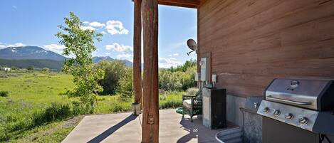 An outdoor patio with a barbecue grill, a wooden pergola, and a view of mountains.