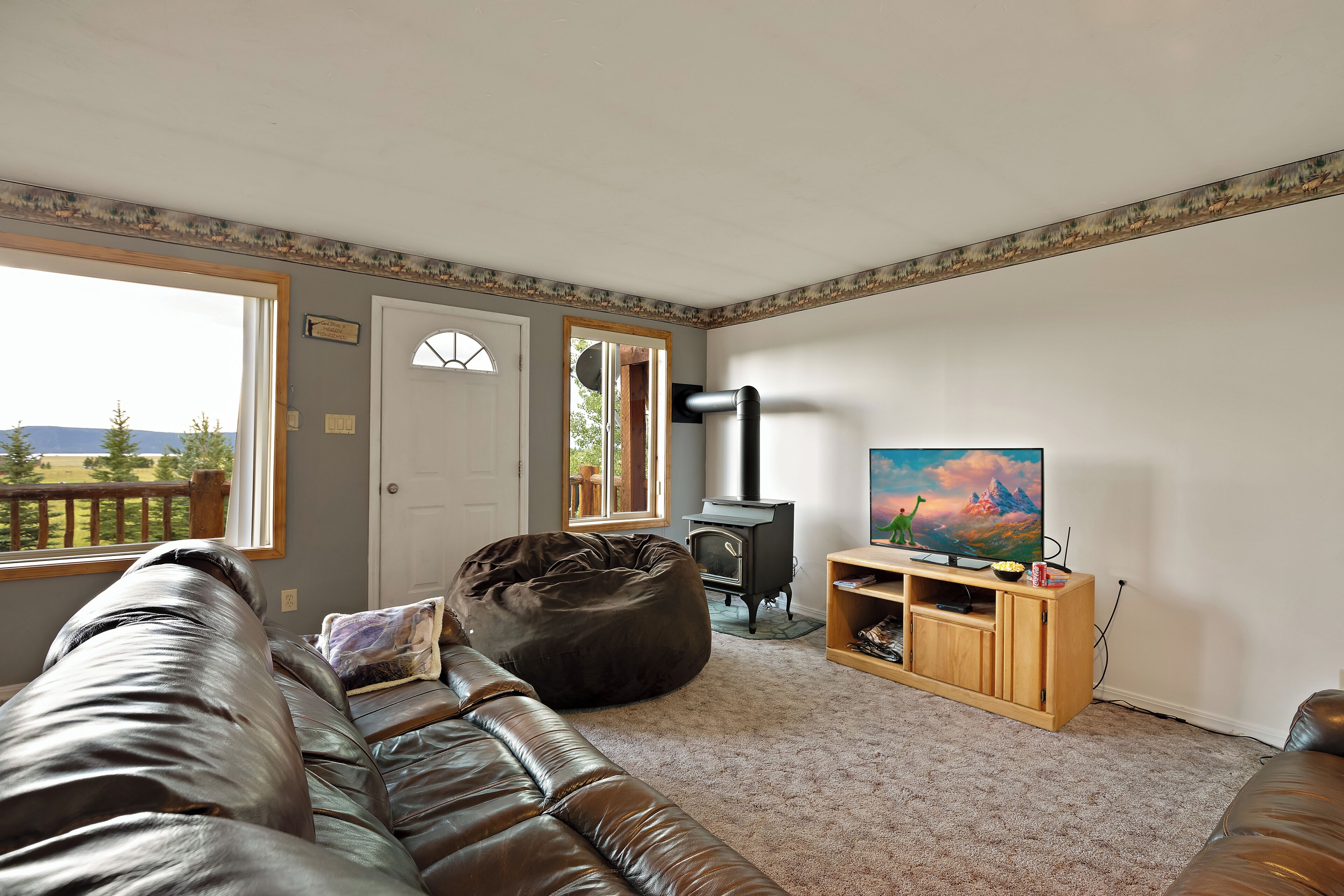 A living room with a leather couch, a bean bag, a fireplace, and a painting on the wall.