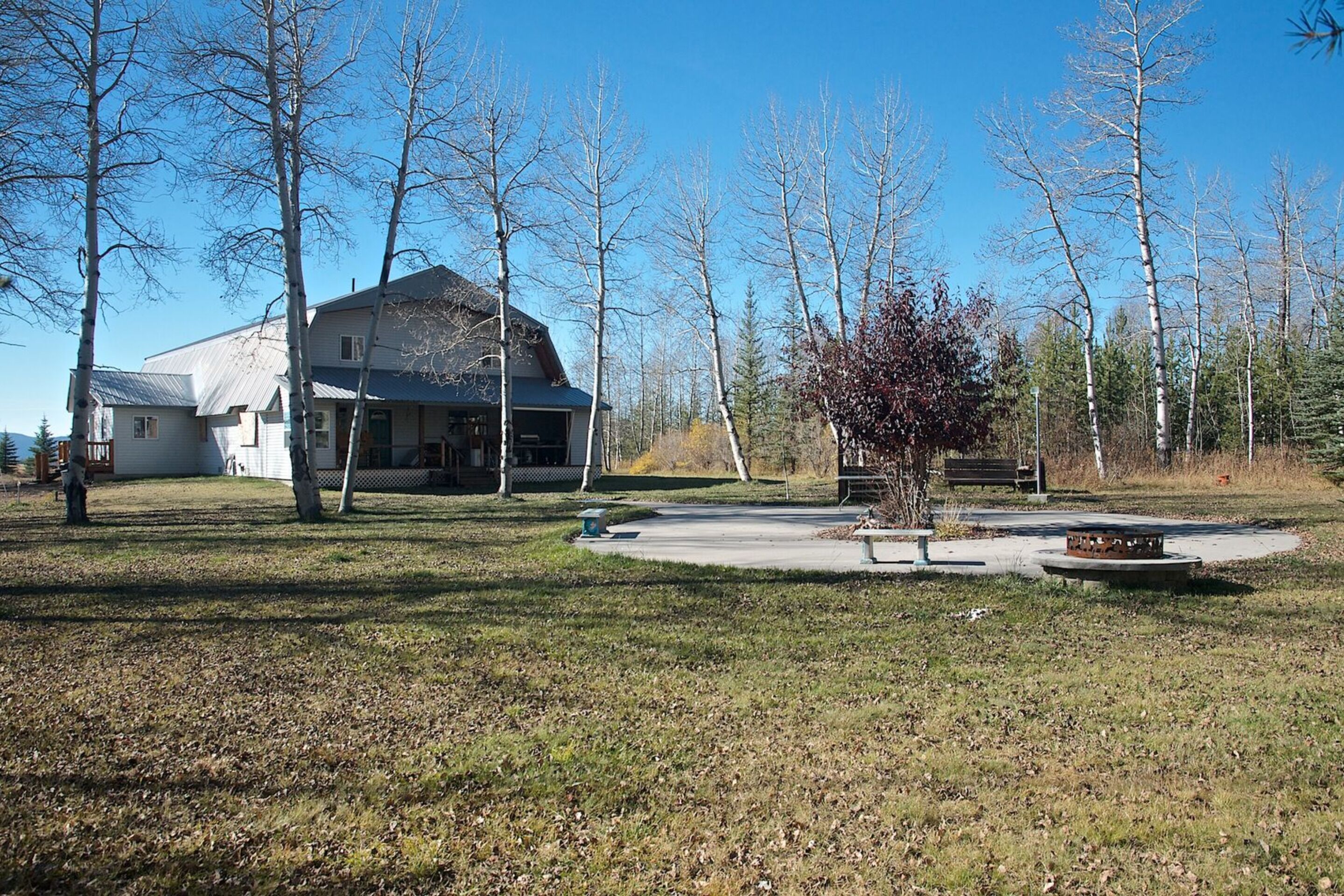 A house with a large front yard, a bench, and a fire pit.