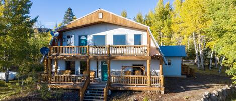 A two-story lodge with a wooden deck and a blue-roofed cabin.