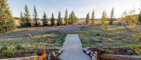 A concrete pathway leading to a road with a wooden fence on either side.