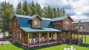 A log cabin with a porch, outdoor seating, and a covered deck area. - Grand View Retreat (Island Park)