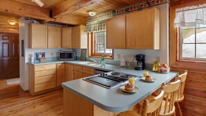 A kitchen with wooden cabinets, a central island, a microwave, and a window with a view of the outdoors. - Grand View Retreat (Island Park)