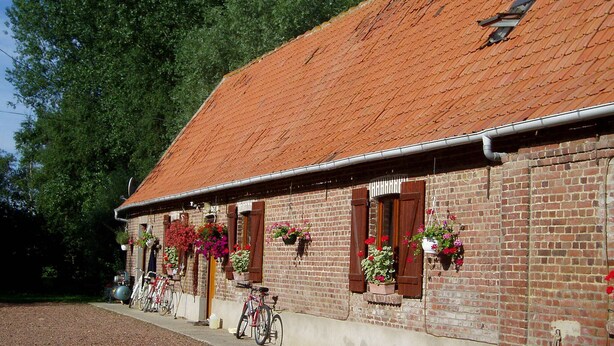 Un edifici de maó amb teulada arajolada, finestres amb balcons florals i bicicletes aparcades a l'exterior.