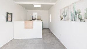 A spacious, modern reception area with a central desk, a wooden panel, and a wall-mounted cactus artwork.