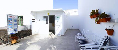 A clean, white outdoor area with a seating area, a door leading inside, and a Jet2 holidays information board.