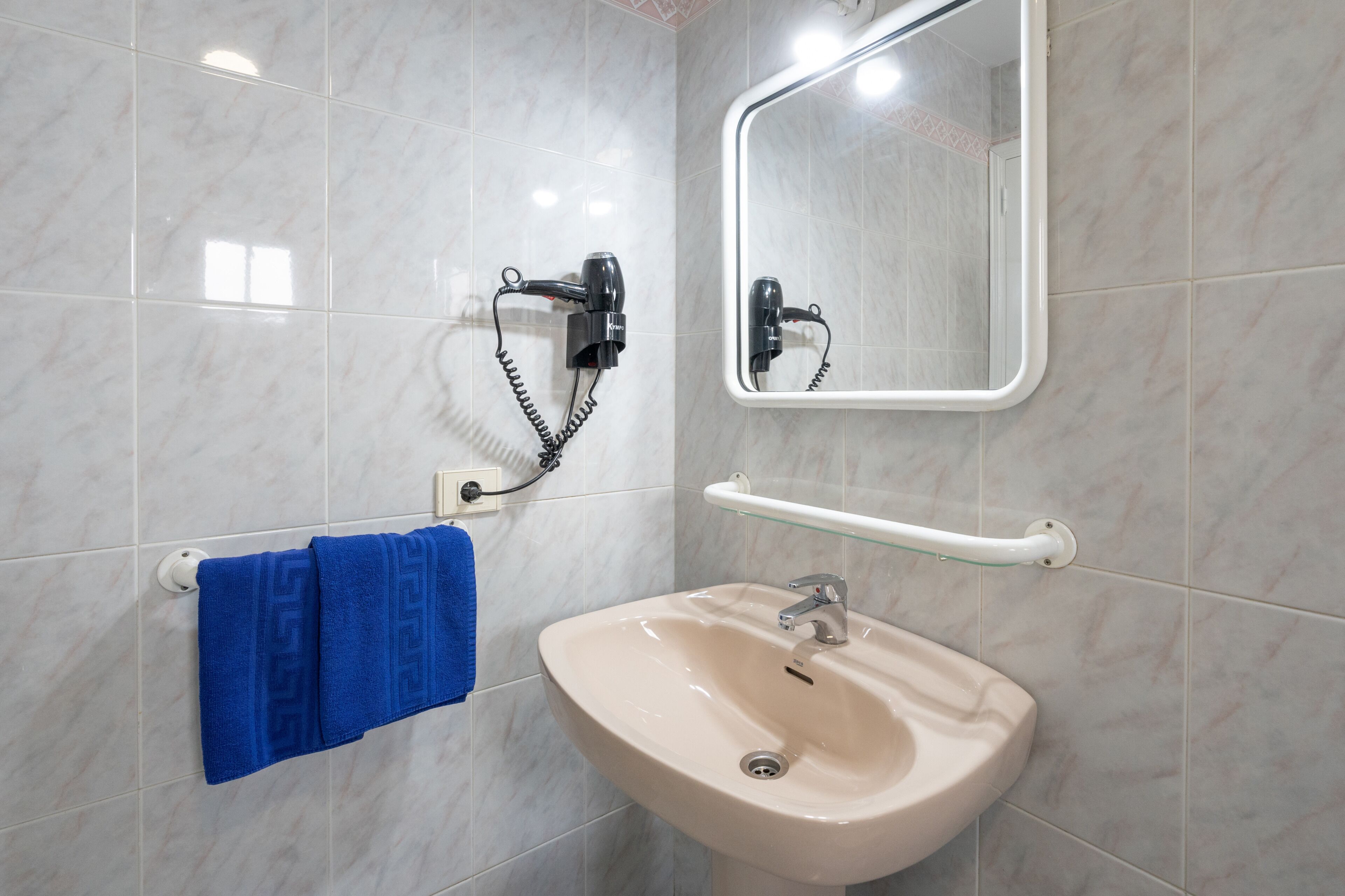 A bathroom with a sink, mirror, towel rack, and hairdryer.
