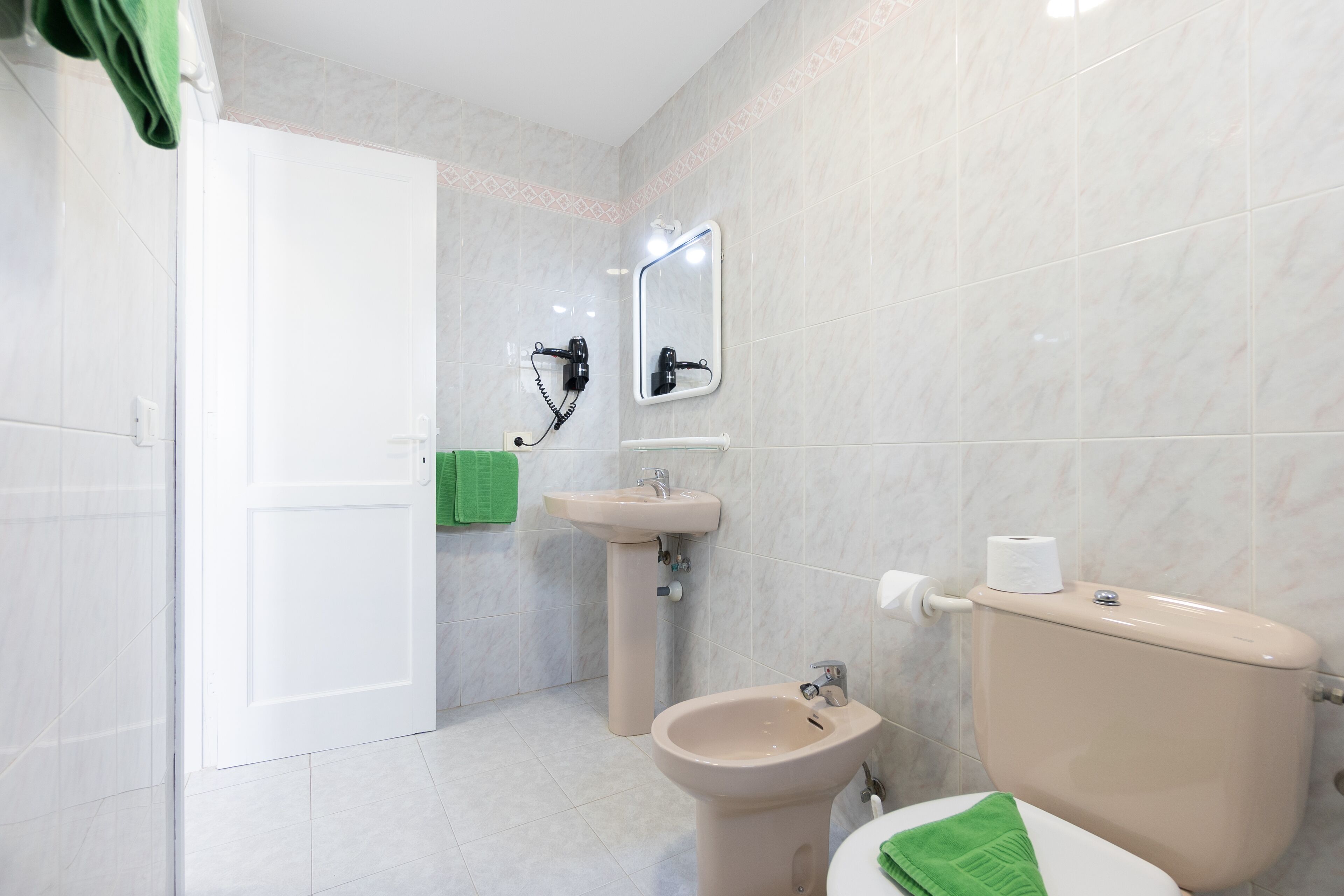 Un baño con inodoro, bidé, lavabo y espejo.