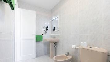 Un baño con inodoro, bidé, lavabo y espejo.