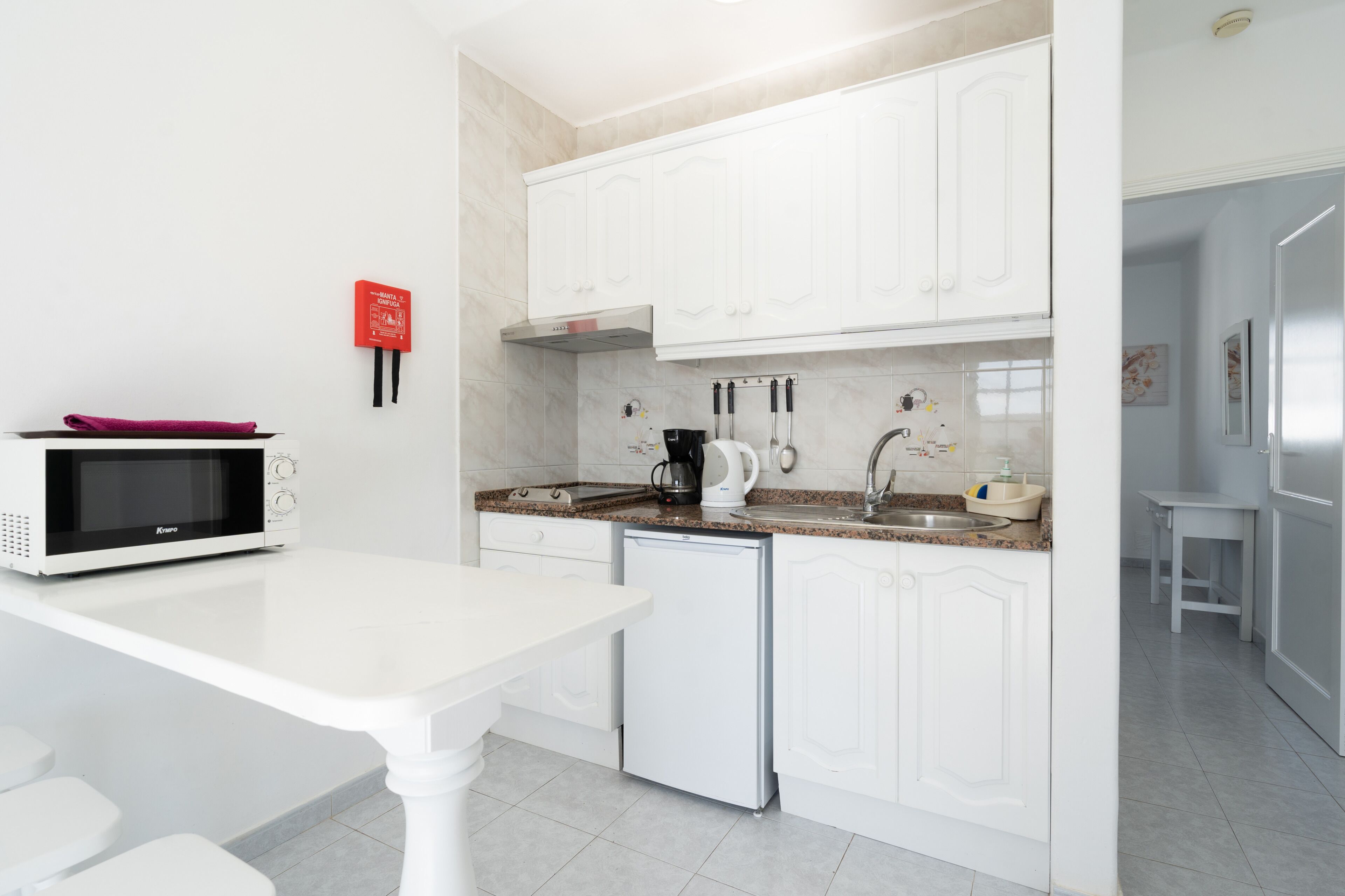 A modern kitchen with white cabinetry, a microwave, a coffee maker, and a dishwasher.