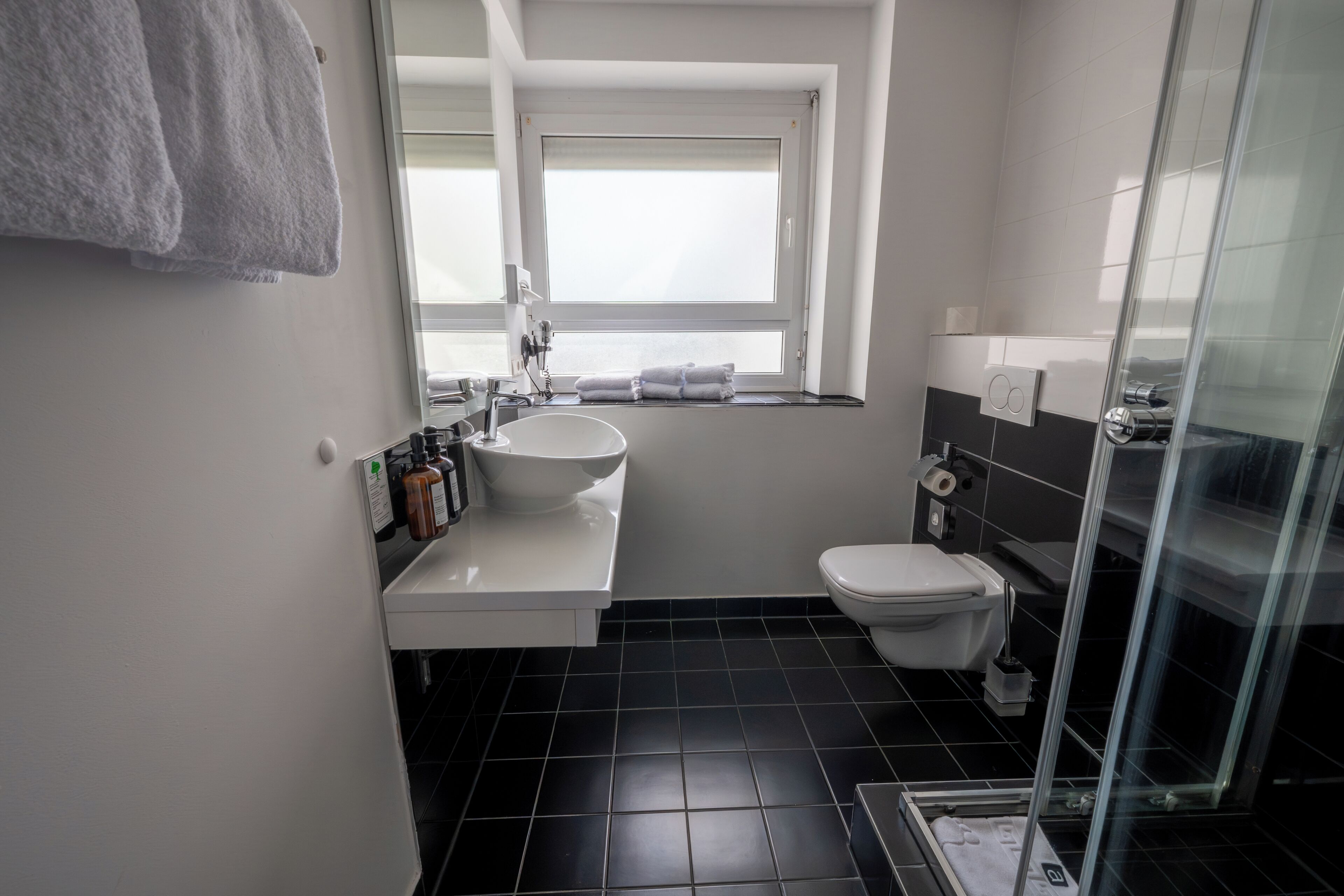 Un baño moderno con un lavamanos blanco, inodoro y cabina de ducha con mampara de cristal.