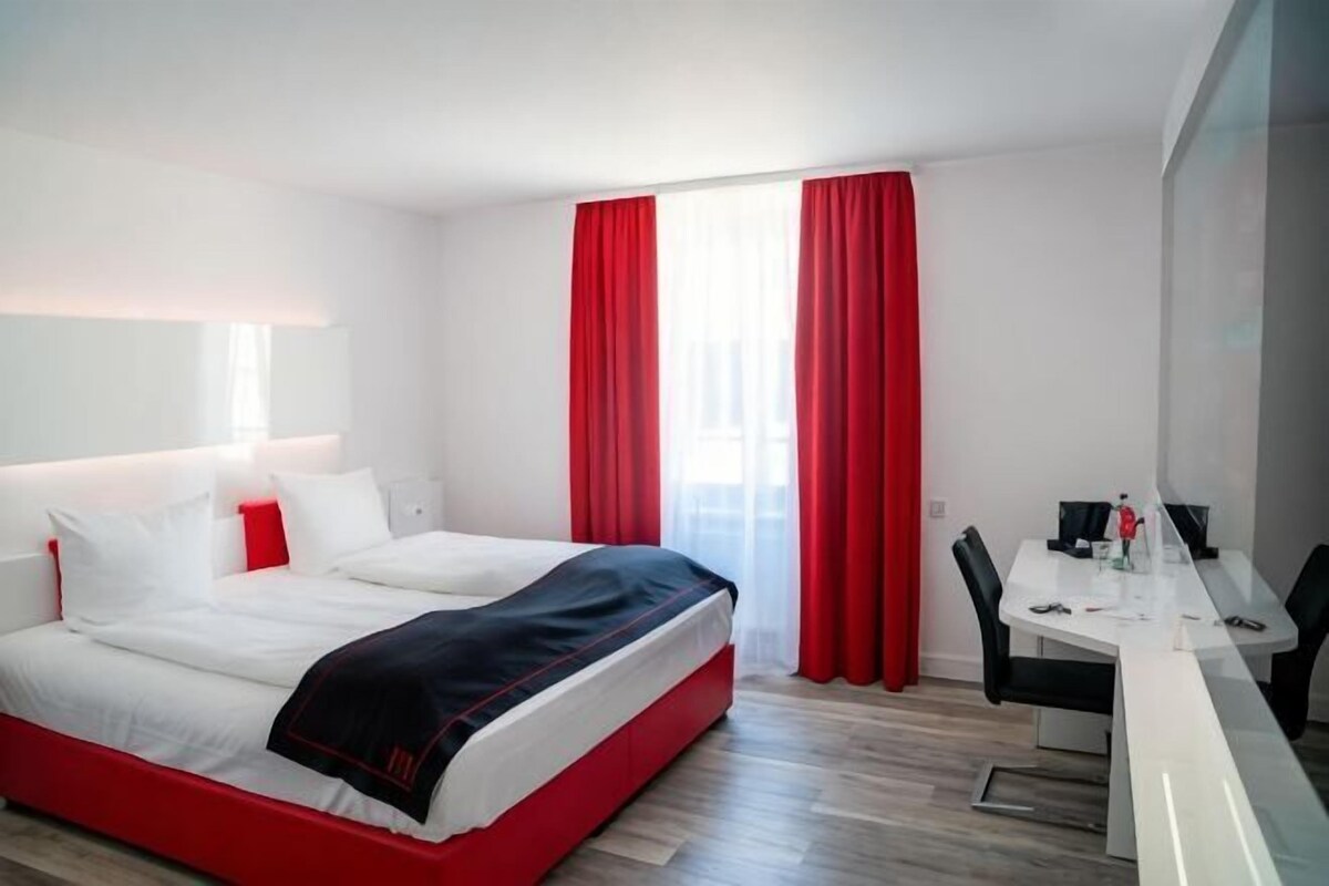 Quarto de hotel moderno com uma cama grande, uma escrivaninha e uma cadeira.