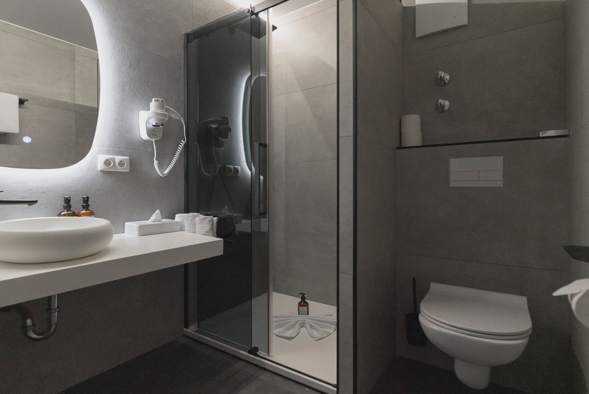 A modern bathroom with a glass shower enclosure, a white sink, and a toilet.