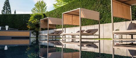 A poolside area with modern lounge chairs and a clear reflection in the water.