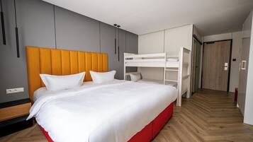 A modern bedroom with a large bed, a bunk bed, and a wooden floor.