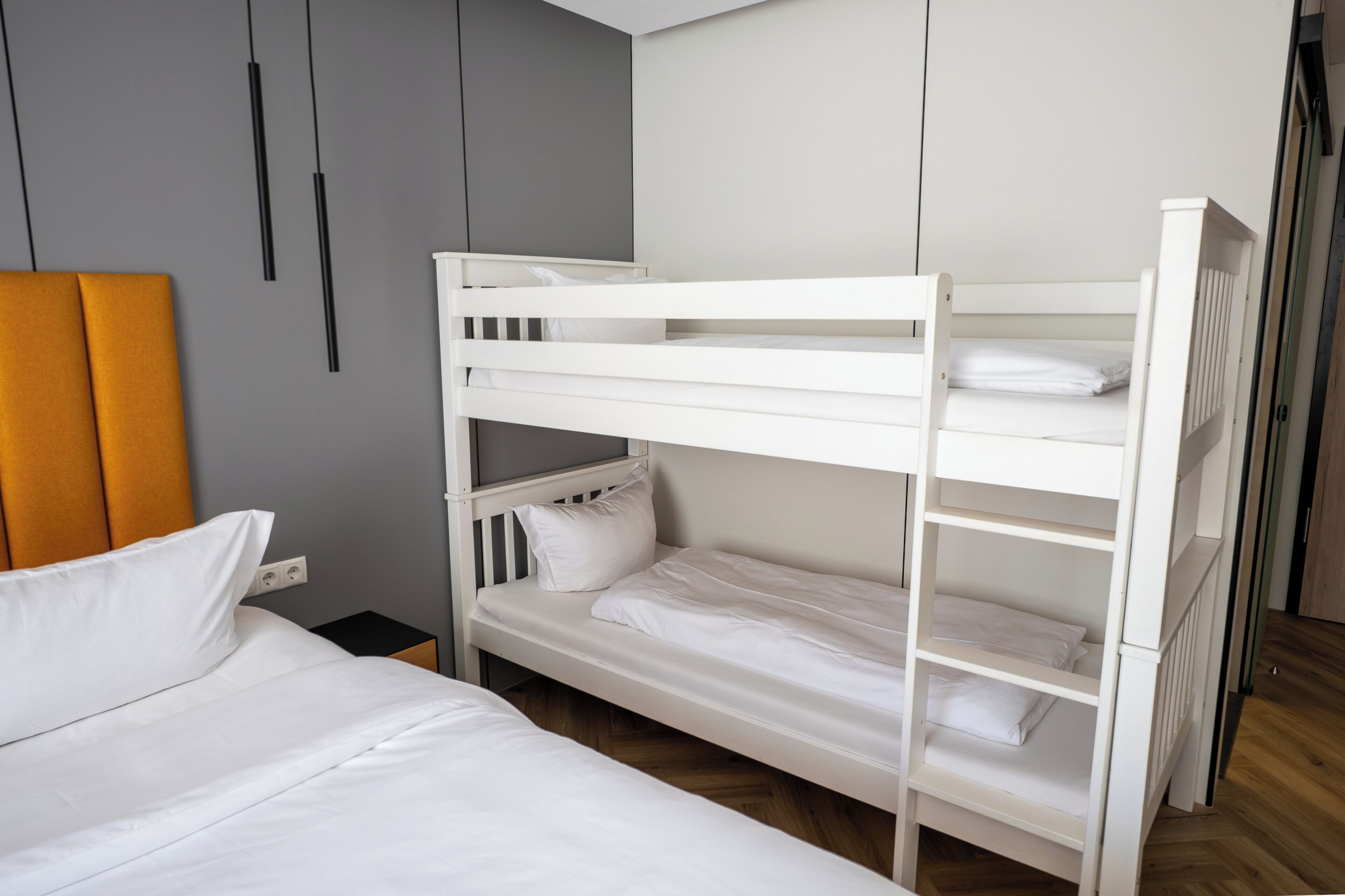 A bunk bed with white bedding and a wooden headboard.