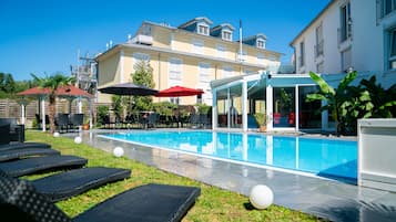 Una piscina al aire libre, sillones reclinables de piscina