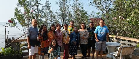 A group of people standing on a wooden deck with a view of the sea.