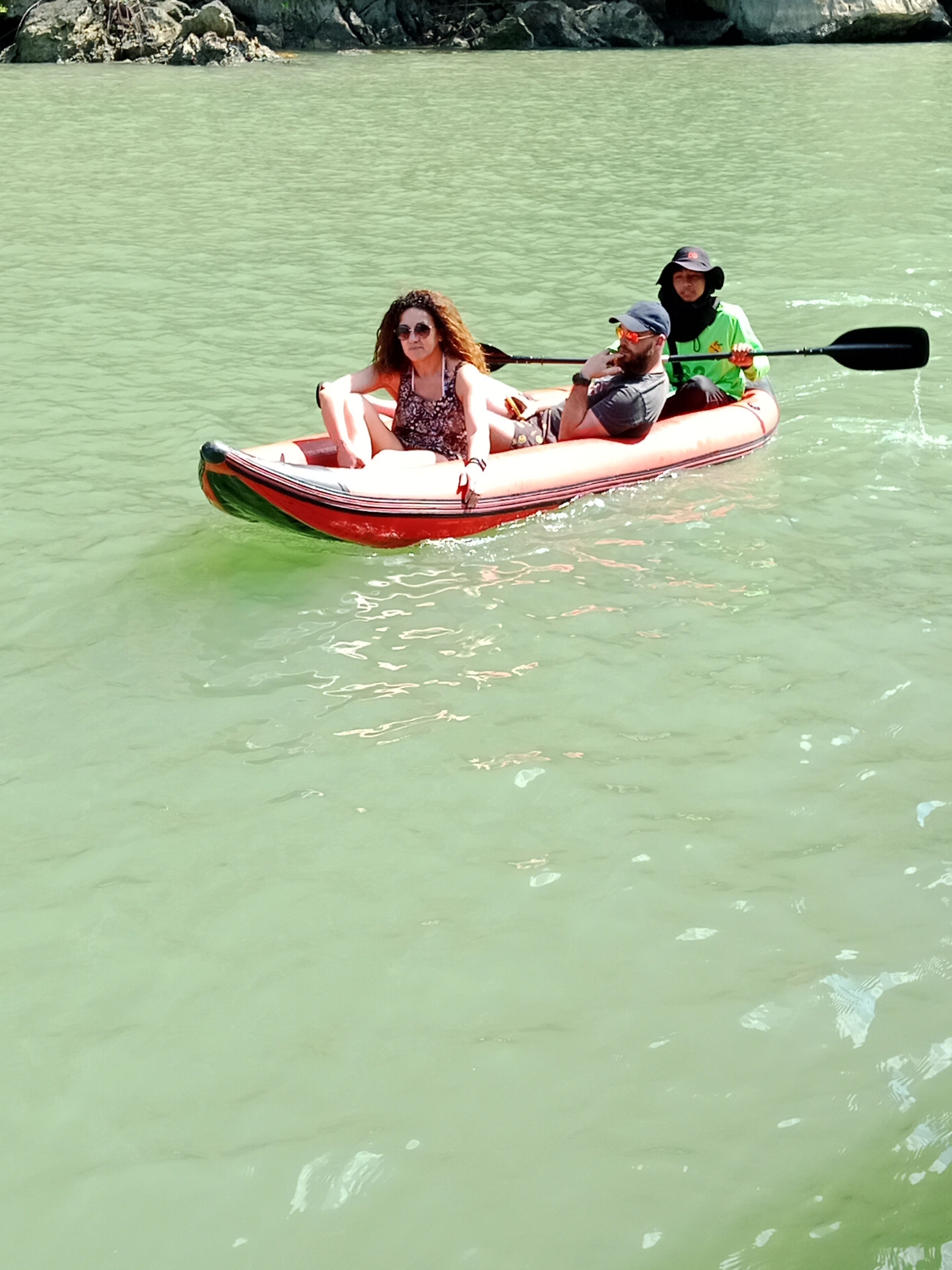 A red inflatable kayak on a calm body of water.