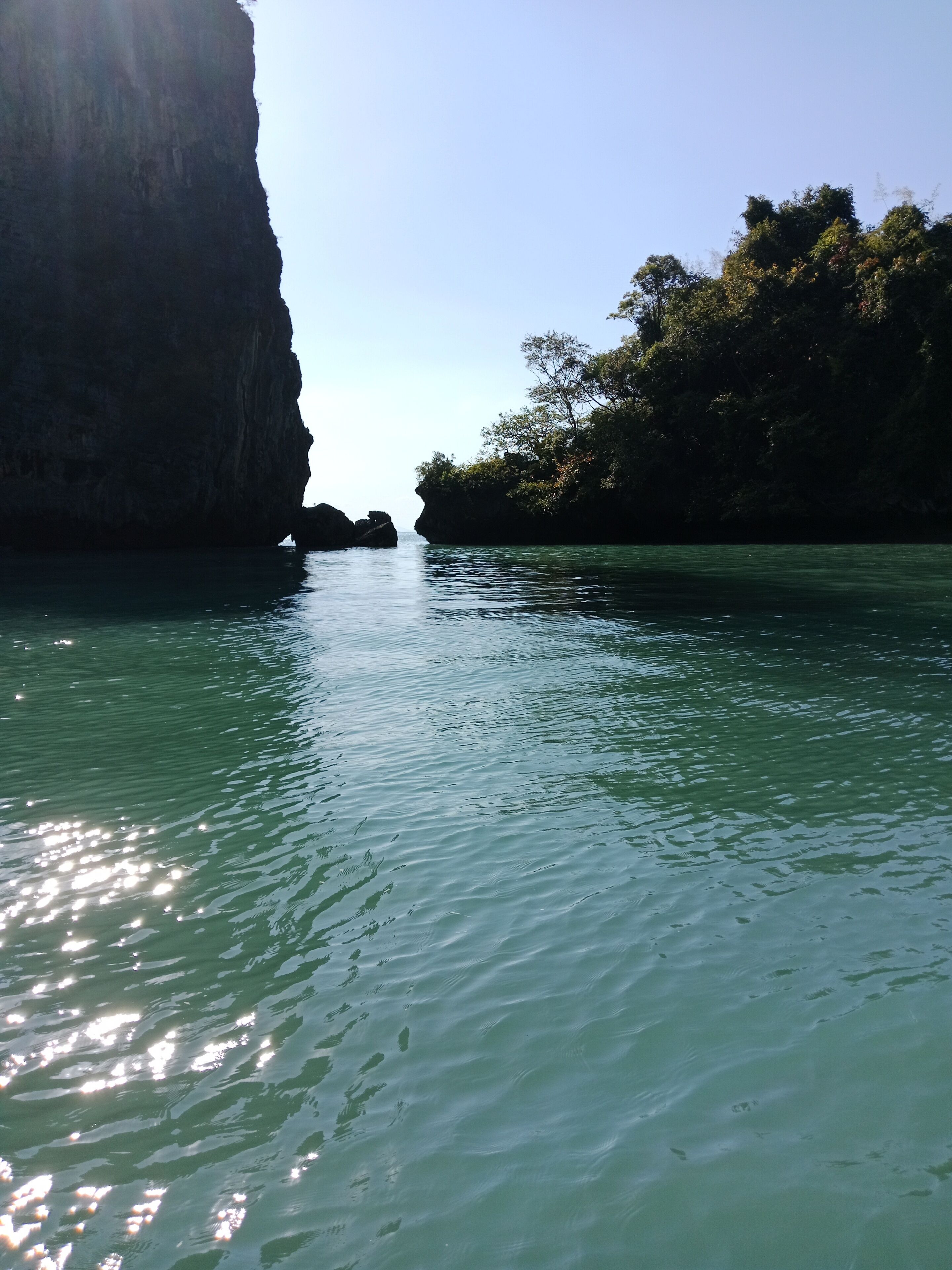 A calm river with clear water, surrounded by rocky cliffs and dense foliage.