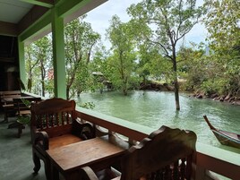 Una mesa y banco de madera dentro de una habitación con vistas a un río y árboles.