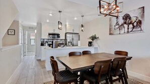 A modern kitchen with white cabinets, stainless steel appliances, and pendant lighting. - Alluring Farmhouse Styled Town Home (McCall)