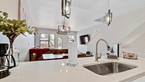 A modern kitchen with a large island, stainless steel sink, and pendant lighting. - Alluring Farmhouse Styled Town Home (McCall)
