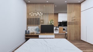 Een moderne slaapkamer met een bed, een televisie, een bureau en een keuken in de achtergrond.
