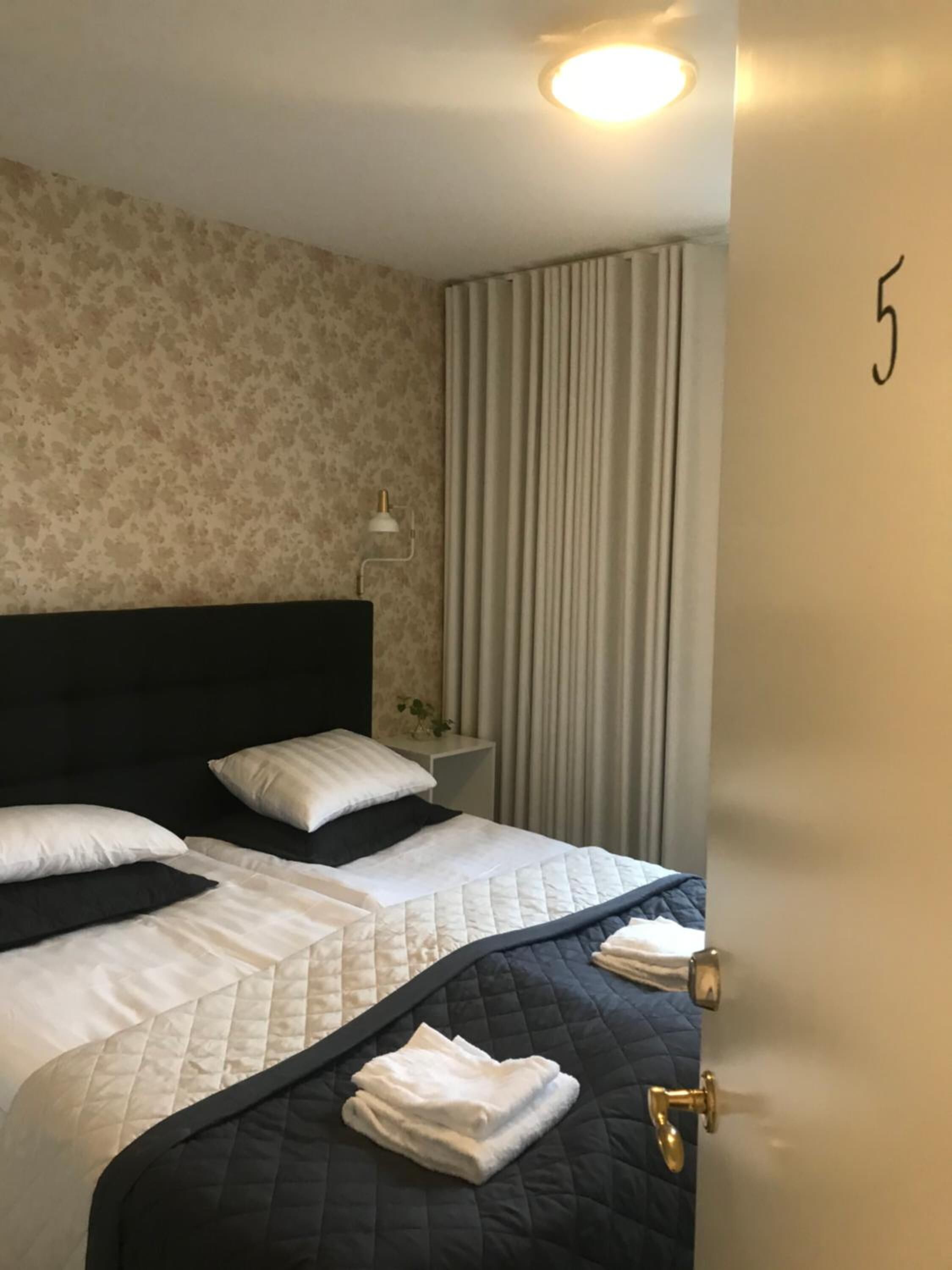 A hotel room with a large bed, a nightstand with a lamp, and a curtain.