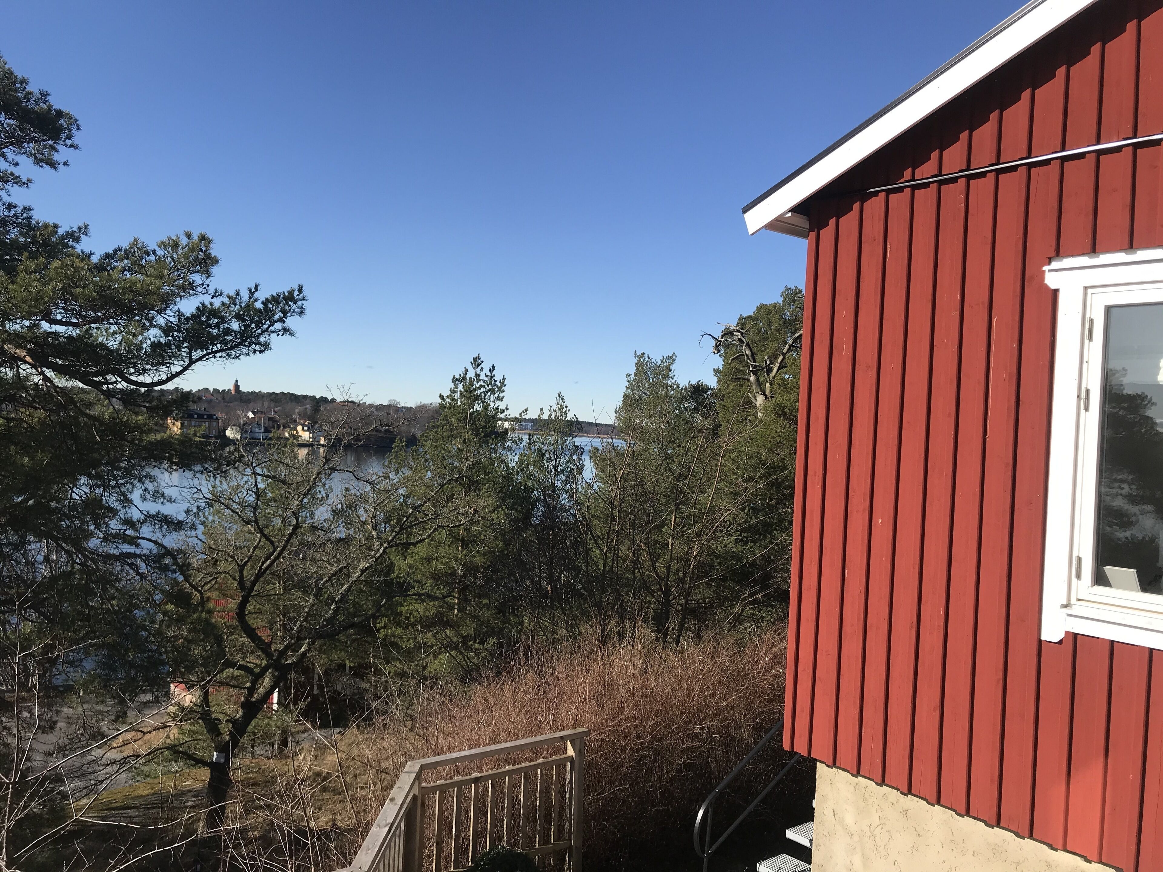 Un bâtiment rouge avec une fenêtre, un escalier en bois et une vue sur un lac et des arbres.