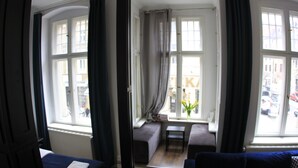 A room with a bed, a sofa, a small table, and a window with curtains. - Apartamenty - Szeroka 31 (Torun)