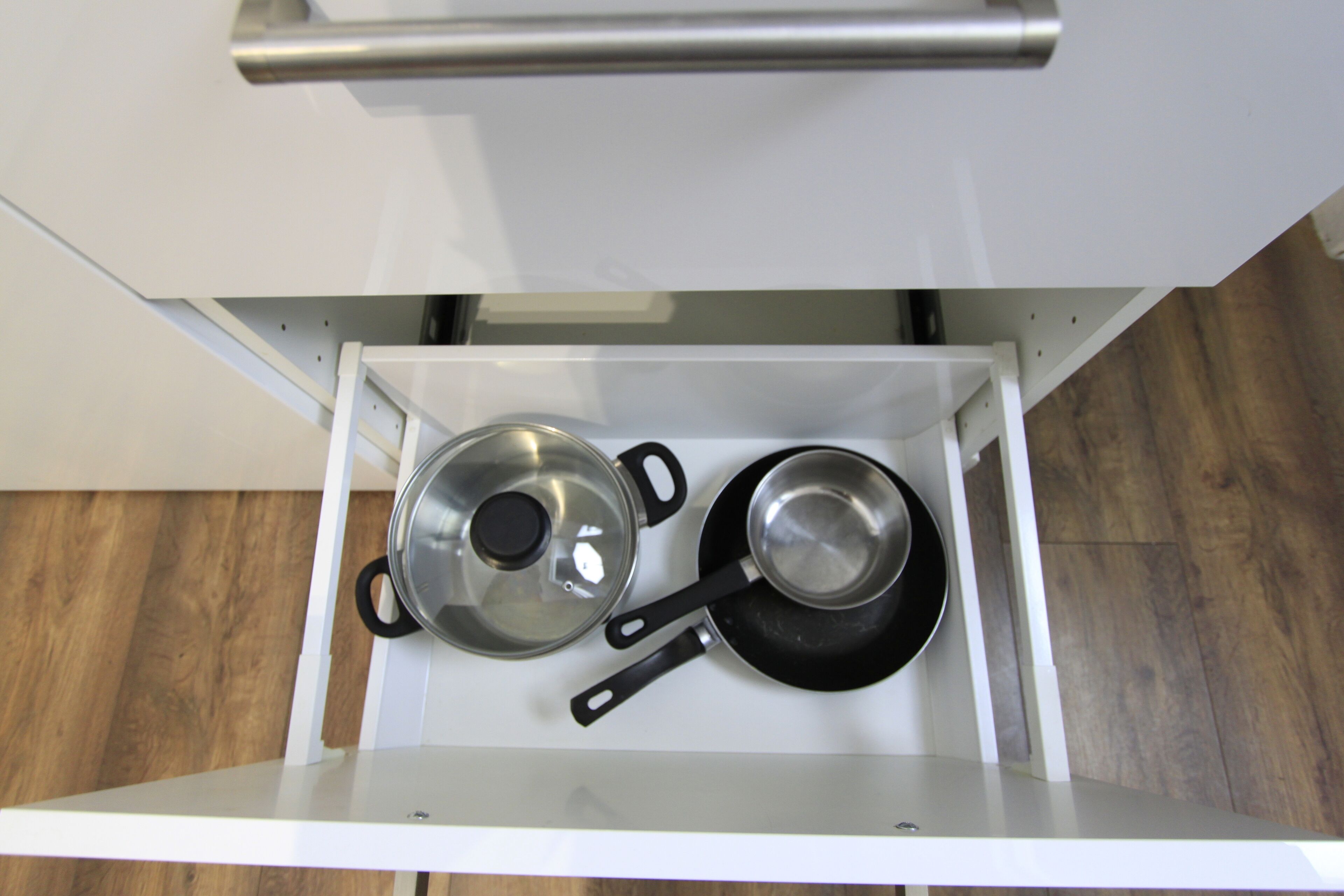 A kitchen drawer with pots and pans.